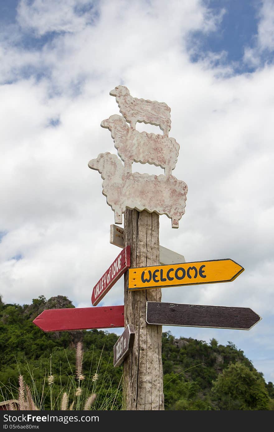 Signs on pole front of mountain and blue sky.