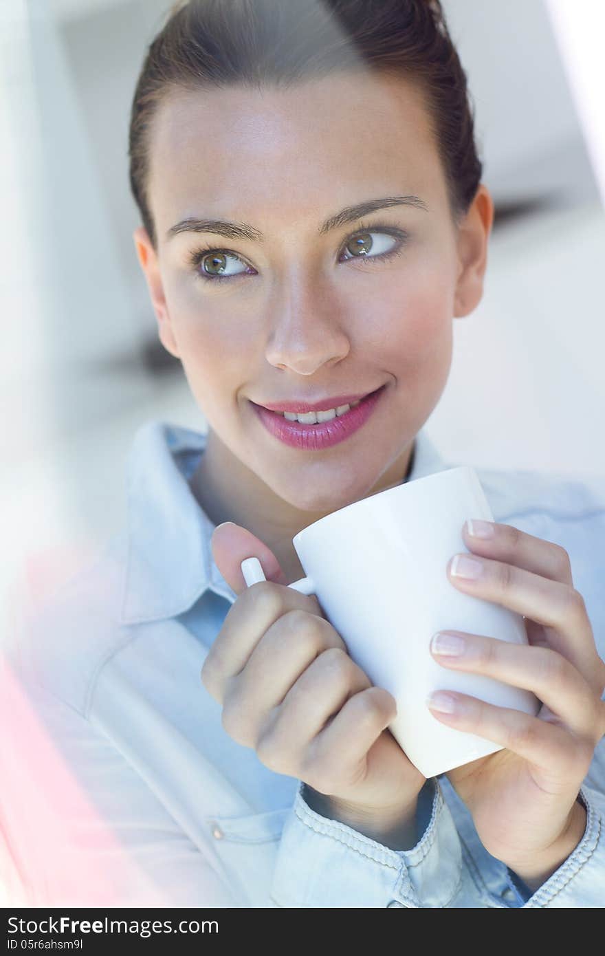 Beautiful young woman having a coffee at the kitchen