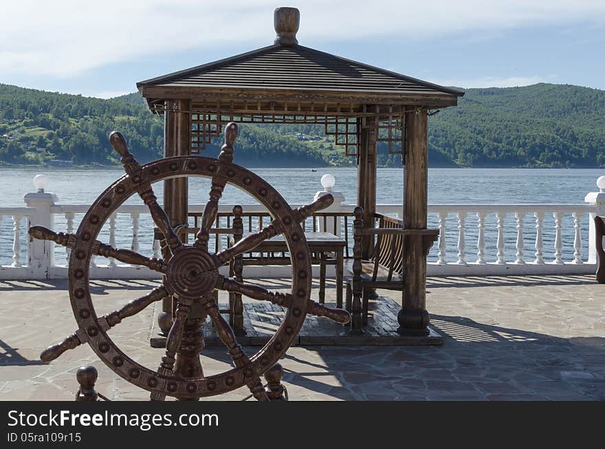 Wooden Arbor With Table And Decorative Helm On The Angara River Shore