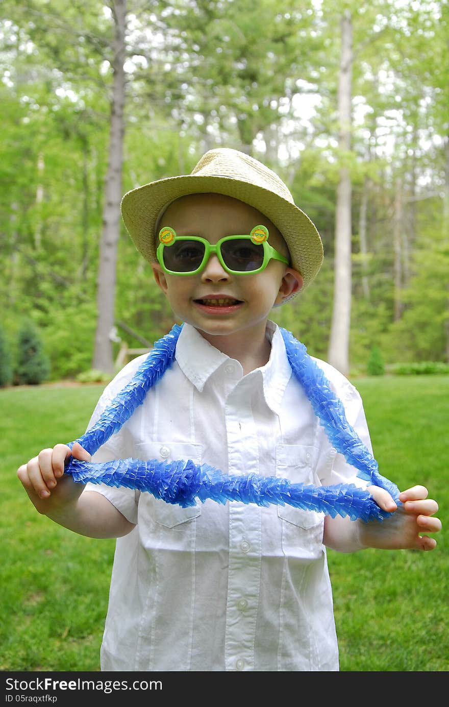 A little boy wears plastic sun glasses and blue hawaian lei. A little boy wears plastic sun glasses and blue hawaian lei