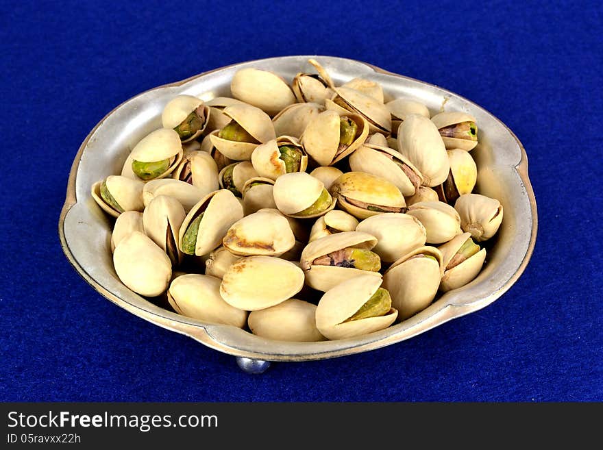 A small metal dish of pistachios in the shell.