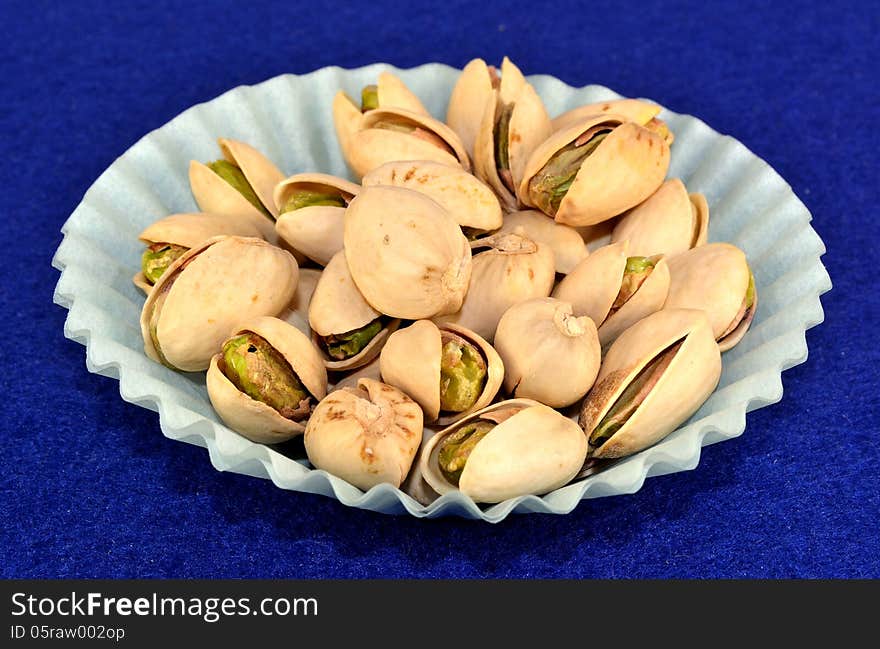 Pistachios in the shell in a blue paper cup.