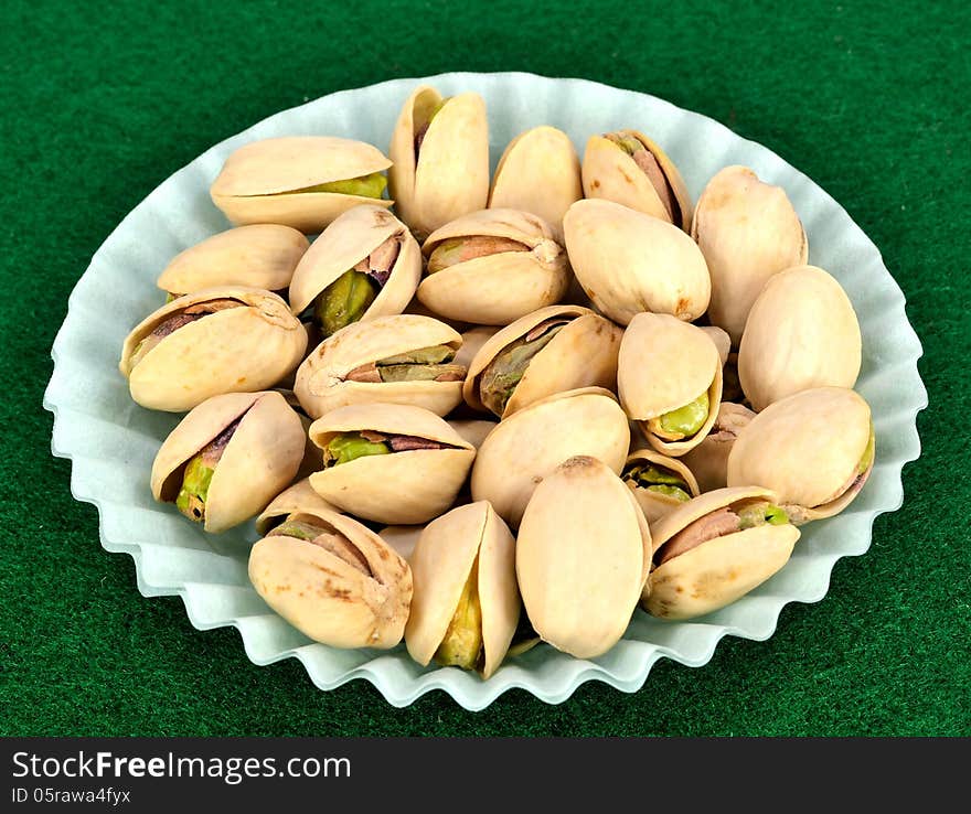 Pistachios in the shell in a blue paper cup.