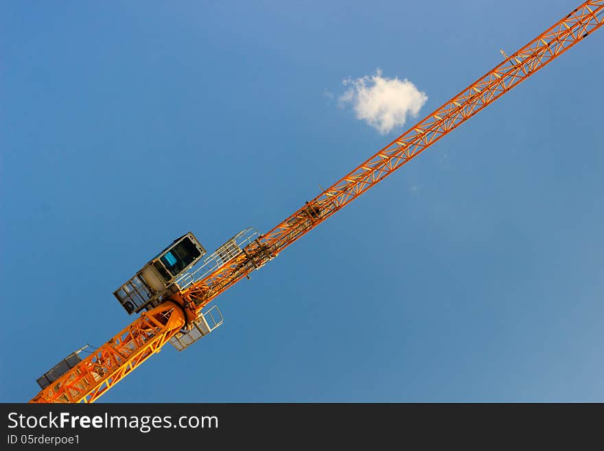 Low angle view of tall crane on modern construction site, blue sky and cloudscape background. Low angle view of tall crane on modern construction site, blue sky and cloudscape background