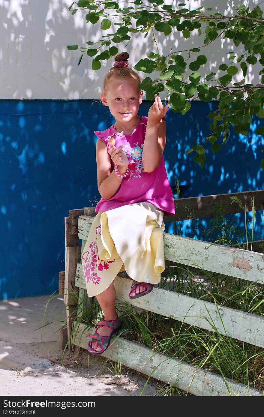 A portrait of a cute little girl holding candy in a tree shade. A portrait of a cute little girl holding candy in a tree shade