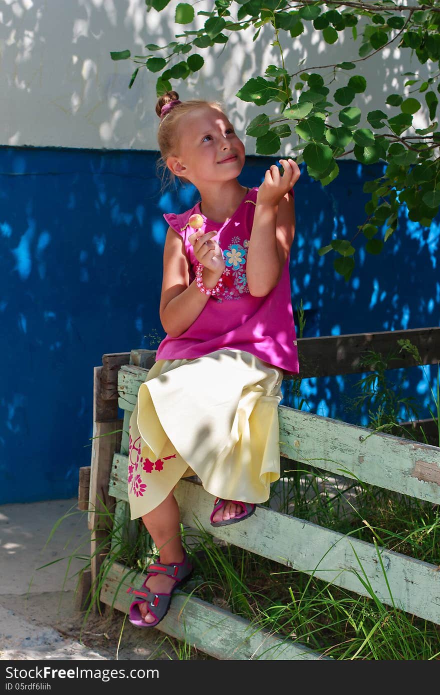 A portrait of a cute little girl holding candy in a tree shade. A portrait of a cute little girl holding candy in a tree shade