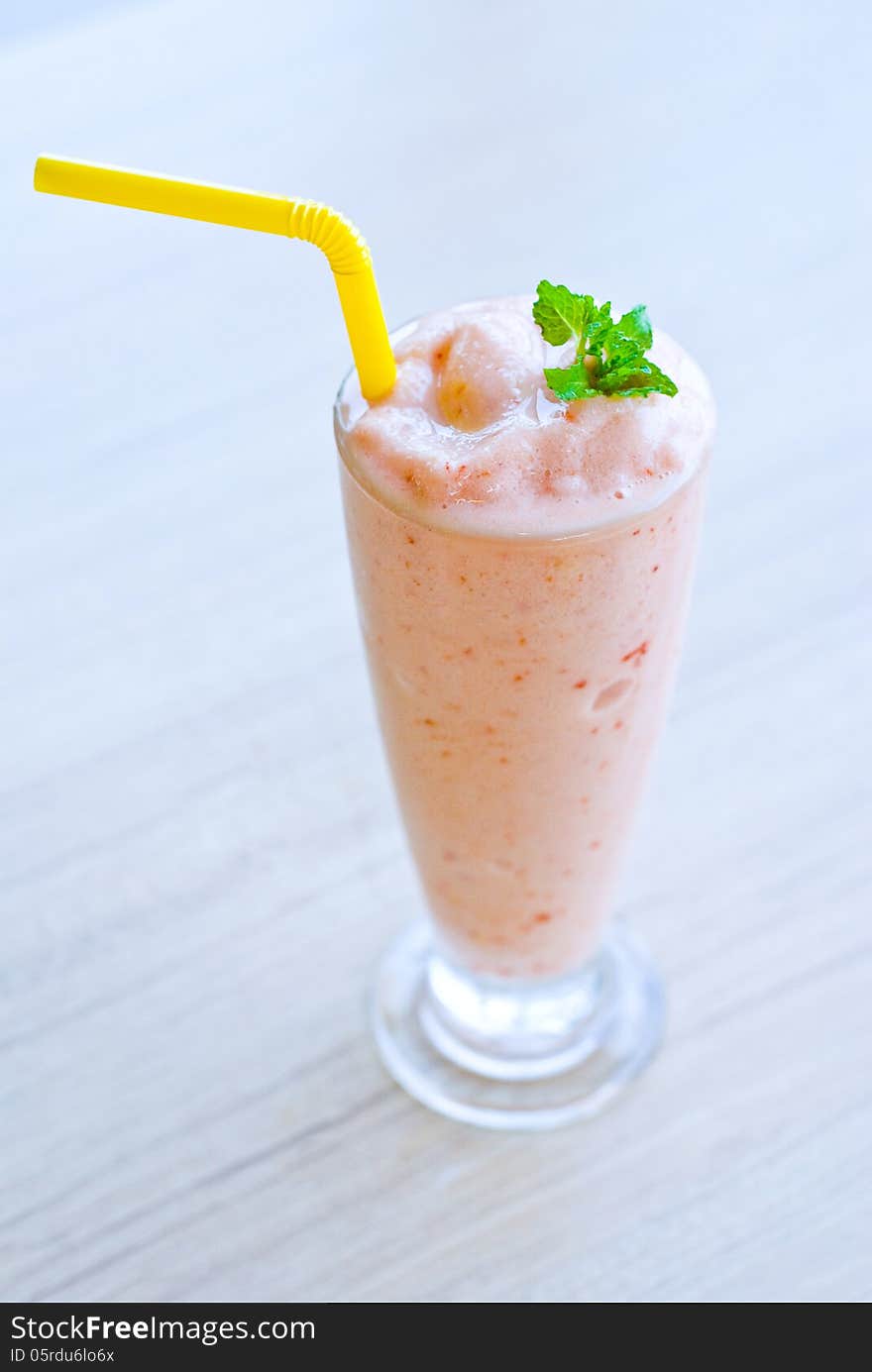 Glass of strawberry smoothie top with pepper mint on table