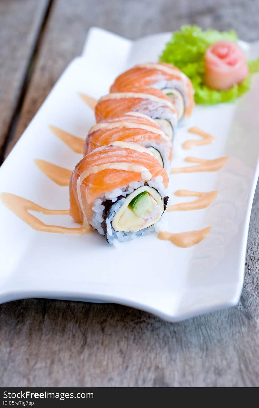 Salmon sashimi roll on white plate topping with cream sauce. Salmon sashimi roll on white plate topping with cream sauce