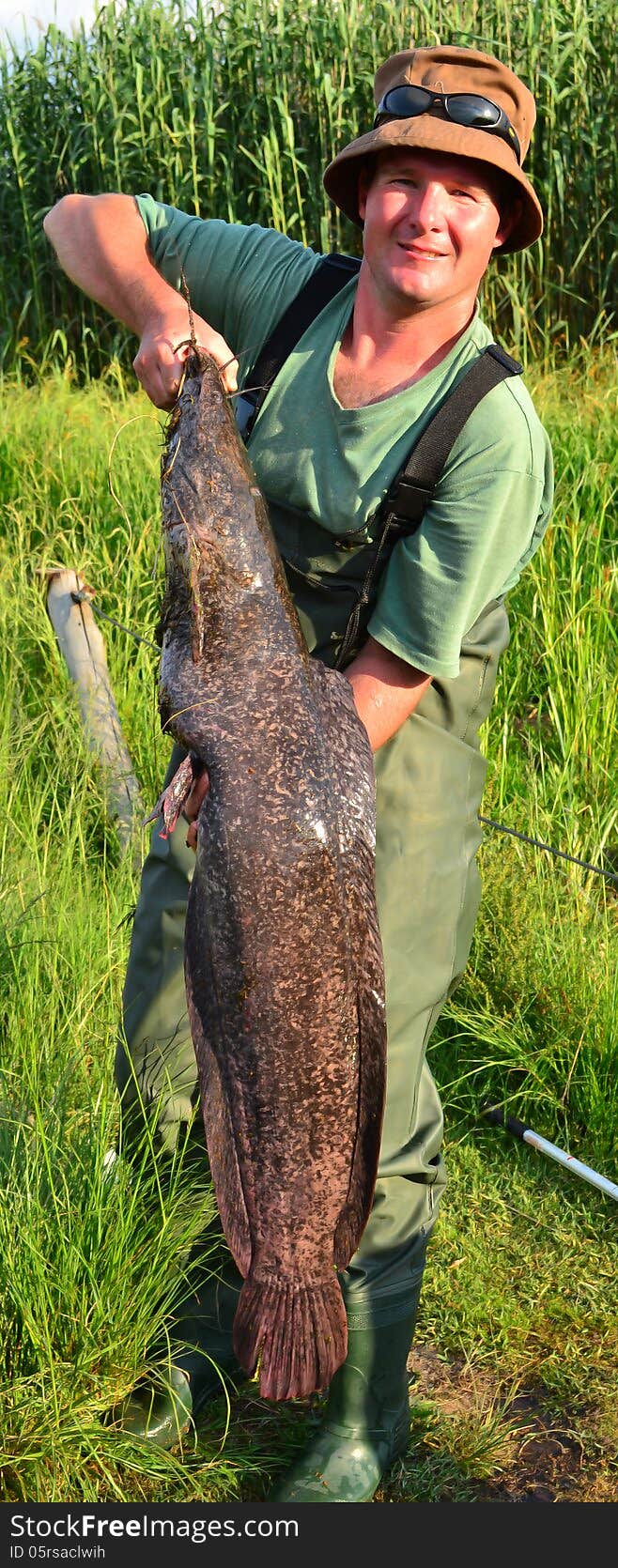 A photo of a fisherman holding up a 12 kg sharp tooth catfish that he caught at a dam. Caught at Rietvlei dam in South Africa on 3 December 2012. A photo of a fisherman holding up a 12 kg sharp tooth catfish that he caught at a dam. Caught at Rietvlei dam in South Africa on 3 December 2012.