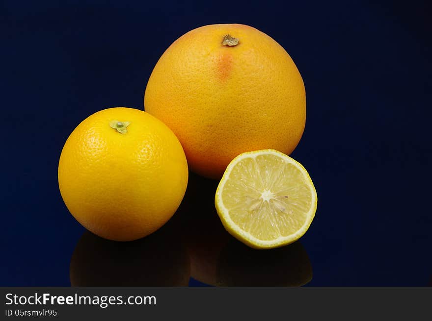 The photograph shows citrus fruits: grapefruit, orange and lemon placed on a blue background. The photograph shows citrus fruits: grapefruit, orange and lemon placed on a blue background.