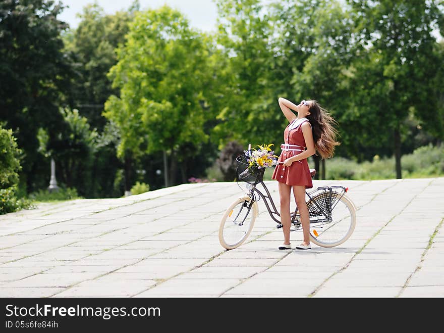 Fashion portrait of young pretty woman with bicycle and flowers