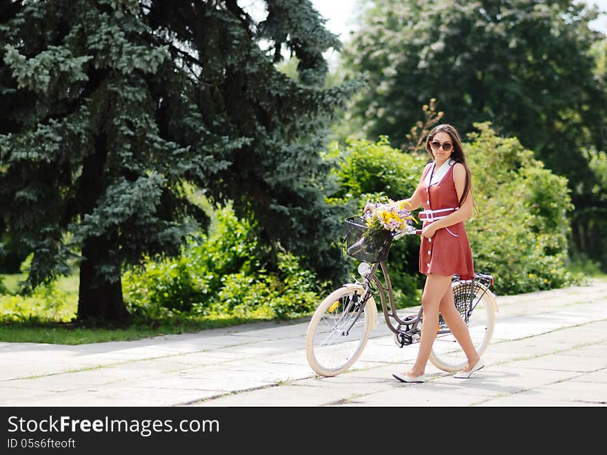 Fashion portrait of young pretty woman with bicycle and flowers