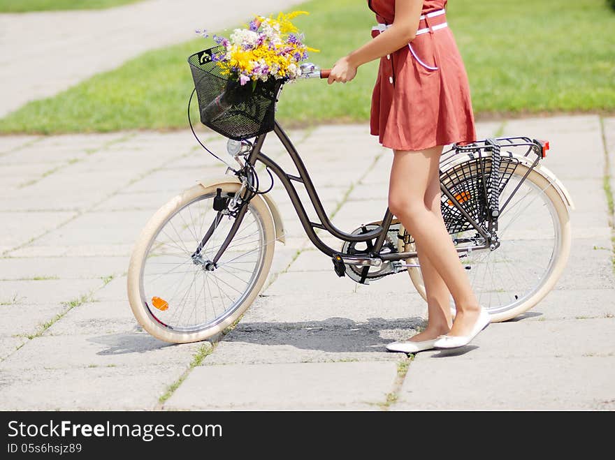 Fashion portrait of young pretty woman with bicycle and flowers