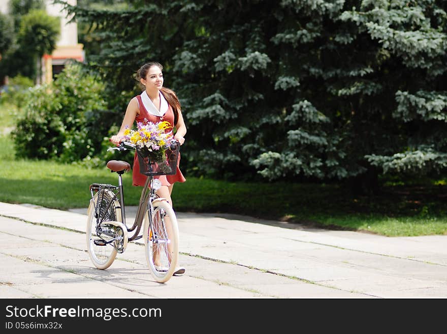 Fashion portrait of young pretty woman with bicycle and flowers