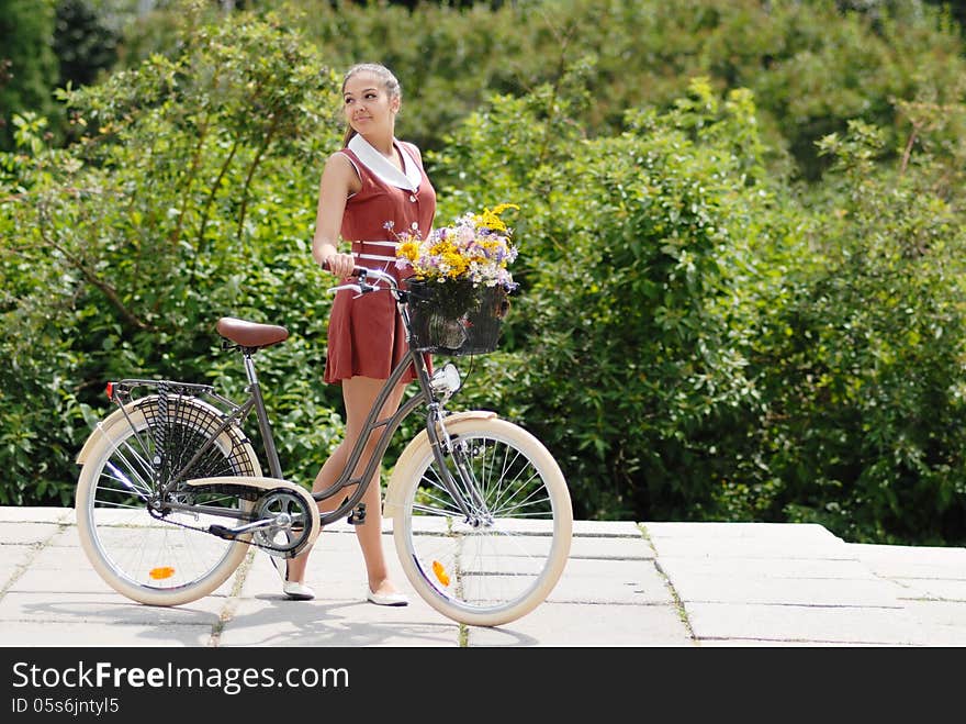 Fashion portrait of young pretty woman with bicycle and flowers