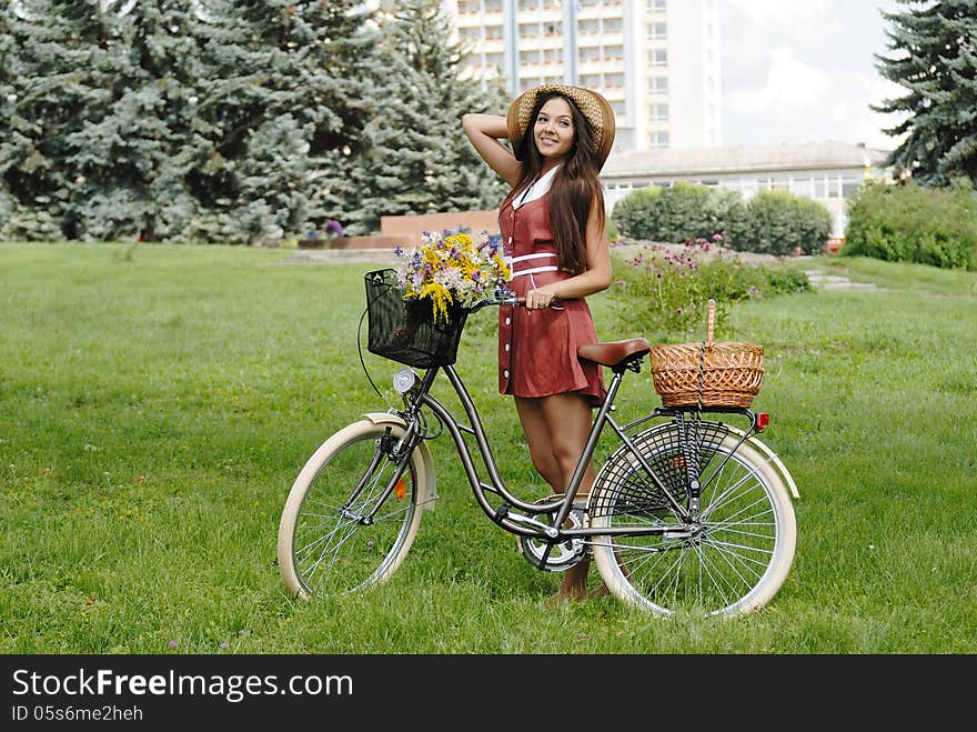 Fashion portrait of young pretty woman with bicycle and flowers