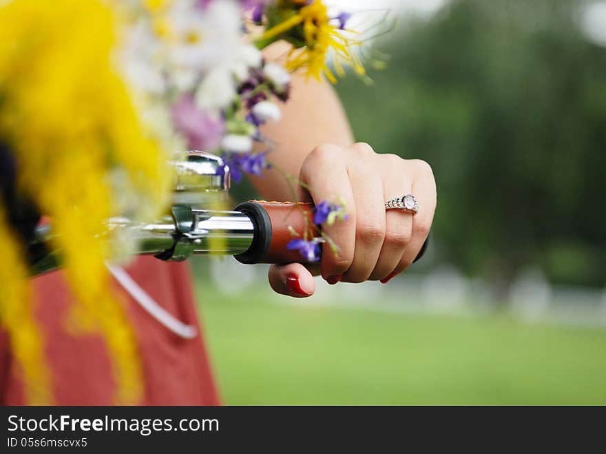 Close-up hand of young pretty woman with bicycle and flowers