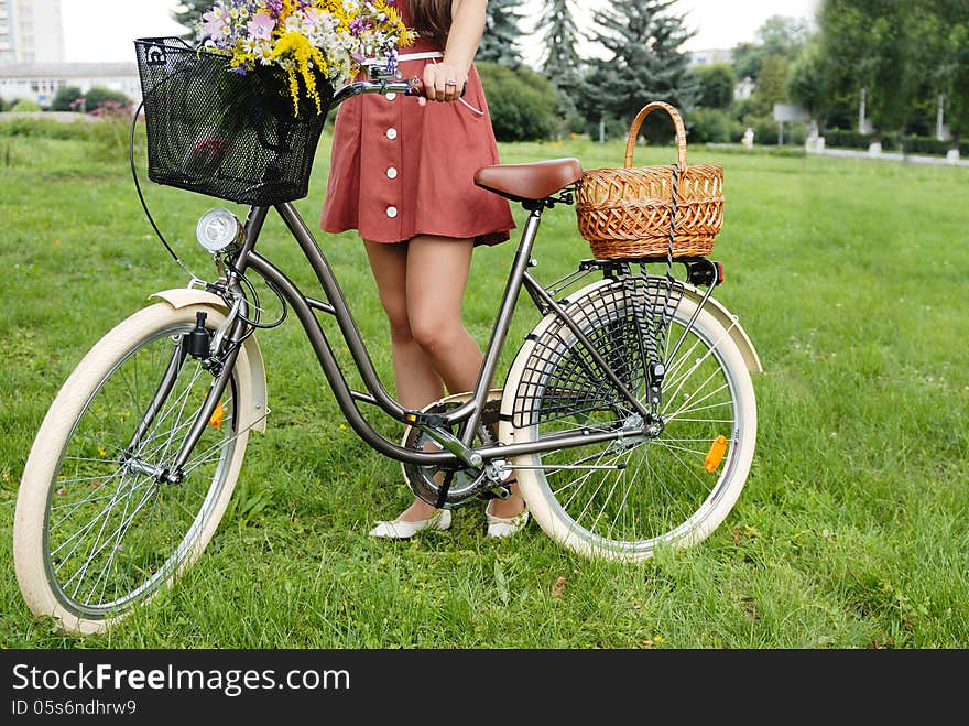 Fashion portrait of young pretty woman with bicycle and flowers