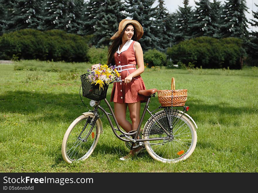 Fashion portrait of young pretty woman with bicycle and flowers