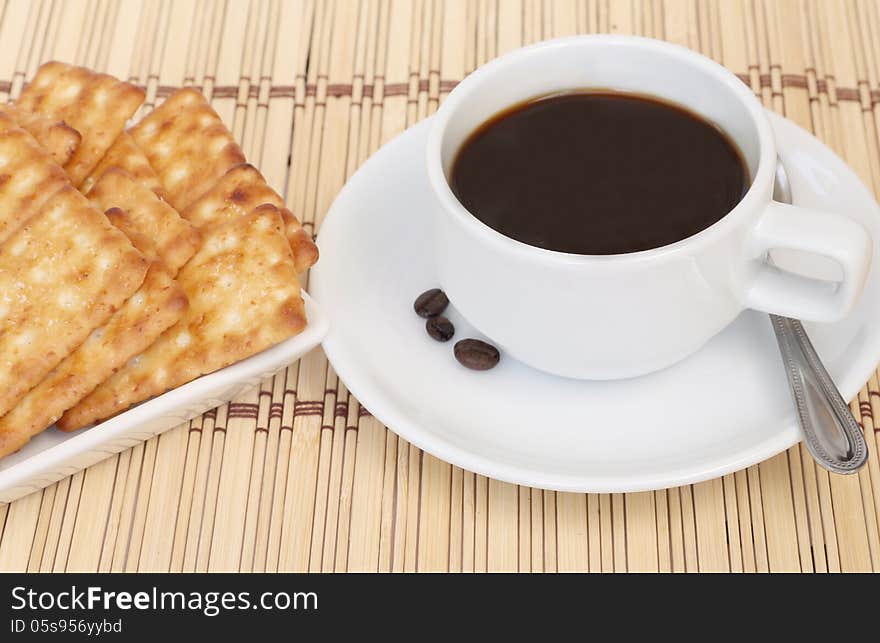 Cup of coffee and cracker on a white plate