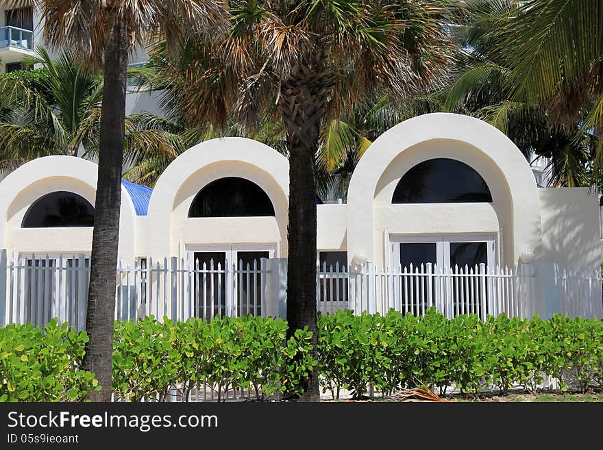 Beautiful palm trees in front of arched doorways in tropical setting with manicured shrubs in front. Beautiful palm trees in front of arched doorways in tropical setting with manicured shrubs in front.