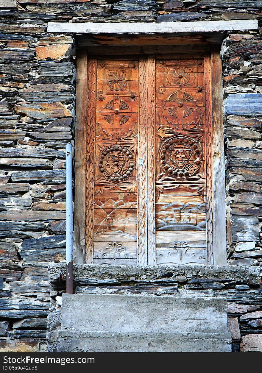 Vintage wooden door with ornament on stone wall background. Georgia