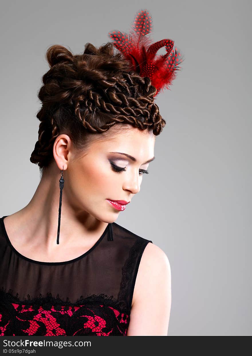 Beautiful adult woman with fashion hairstyle with red feather in hairs