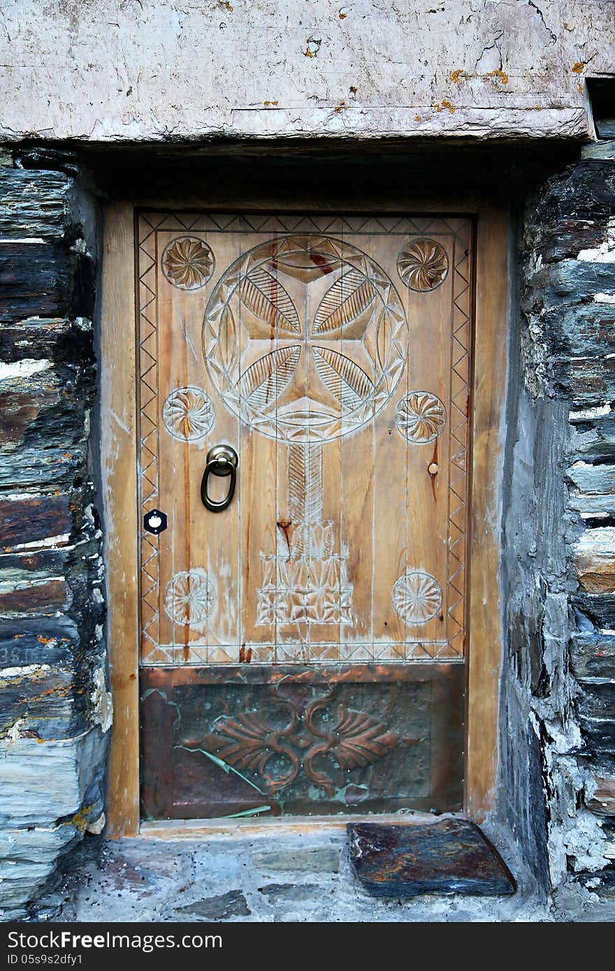 Vintage wooden door with ornament on stone wall background