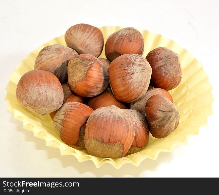 A small paper cup of hazelnuts in the shell.