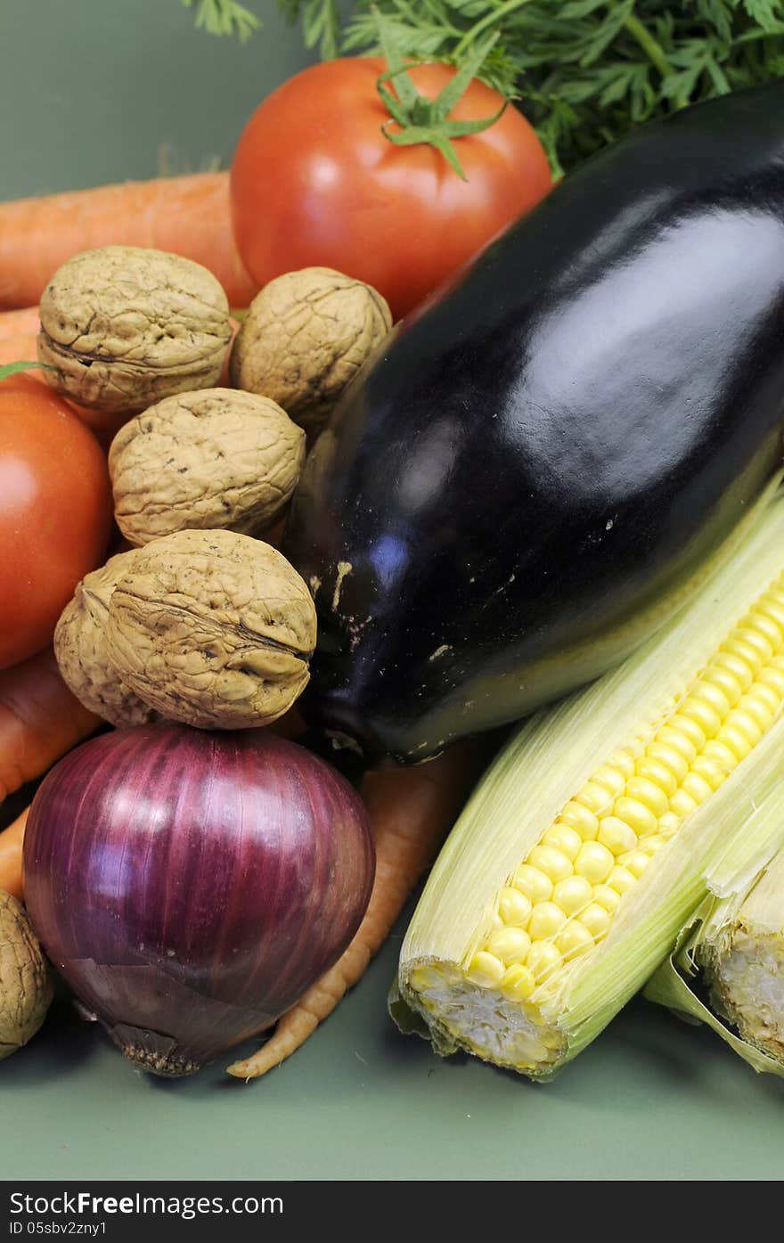 Fresh raw food including eggplant, mulnuts nuts carrots tomotoes and corn for healthy diet concept or World vegetarian Day on October 1. Vertical close up. Fresh raw food including eggplant, mulnuts nuts carrots tomotoes and corn for healthy diet concept or World vegetarian Day on October 1. Vertical close up.