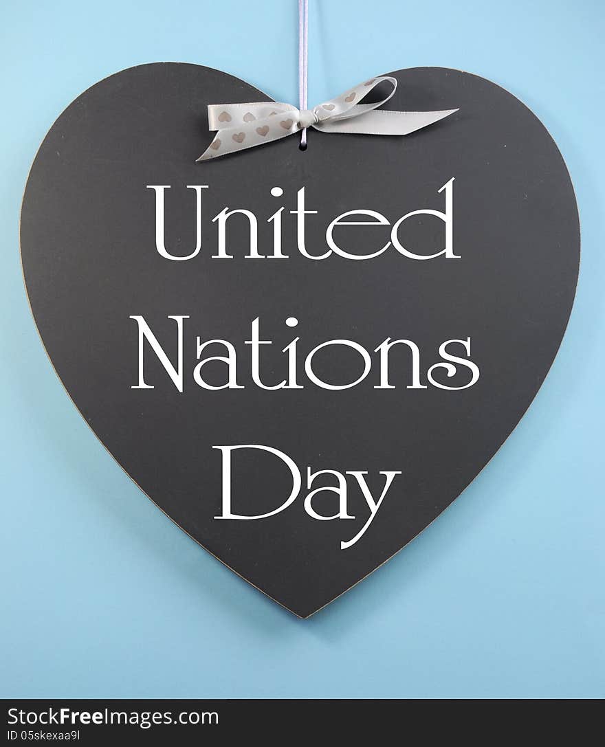 United Nations Day text message greeting written on heart shape blackboard against a sky blue background.