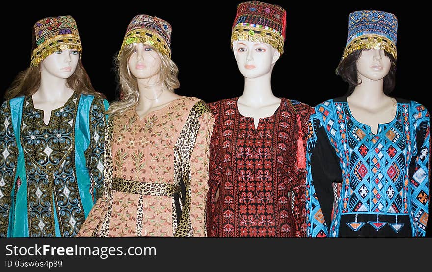 Four mannequins wearing traditional colorful Turkish costumes with headdresses, . Black background. Four mannequins wearing traditional colorful Turkish costumes with headdresses, . Black background.