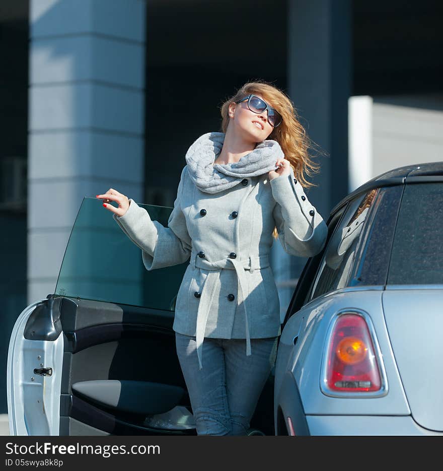 Young beautiful woman standing next to his gray car. Young beautiful woman standing next to his gray car