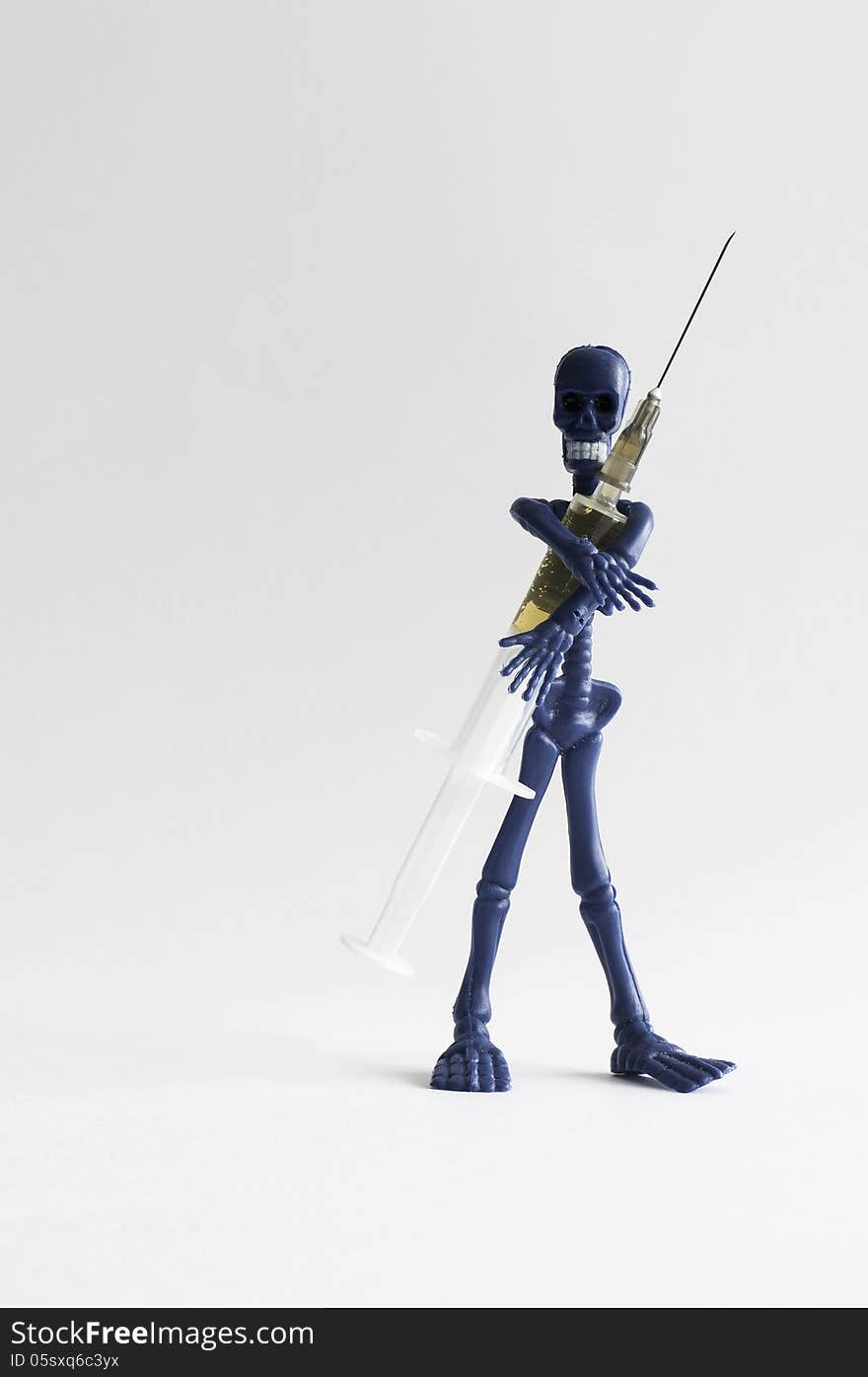 Blue rubber skeleton standing with syringe filled with transparent liquid. Blue rubber skeleton standing with syringe filled with transparent liquid