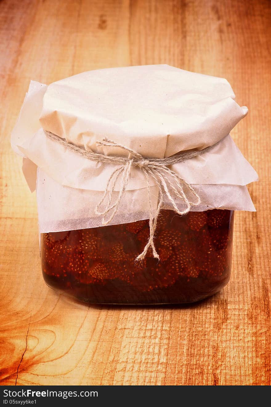 Wild Strawberry Jam Jar Covered with Butter-paper isolated on Wooden background