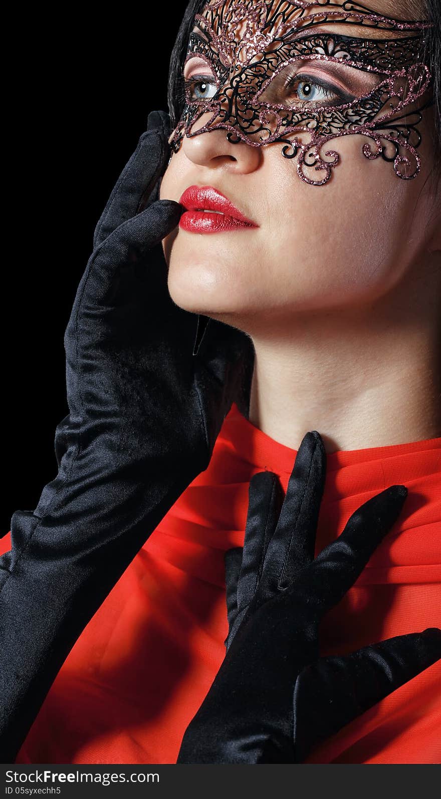 Girl in a Venetian masquerade mask isolated on a black background. Girl in a Venetian masquerade mask isolated on a black background