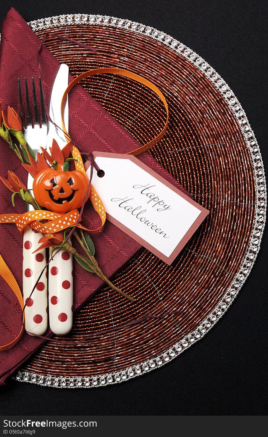 Happy Halloween table place setting with red polka dot cutlery and pumpkin decorations on a black tablecloth, Vertical. Happy Halloween table place setting with red polka dot cutlery and pumpkin decorations on a black tablecloth, Vertical.