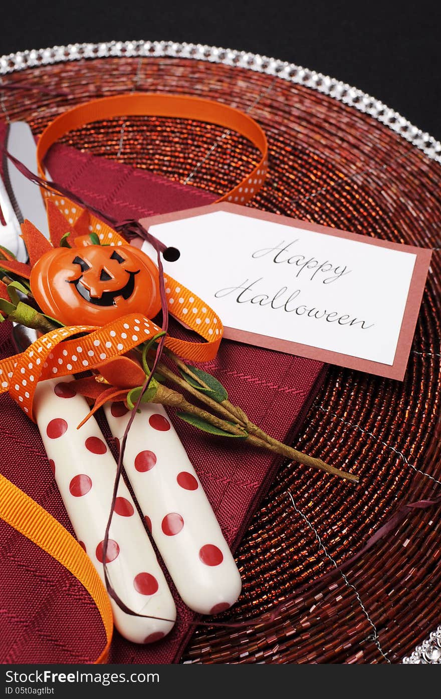 Happy Halloween table place setting with red polka dot cutlery and pumpkin decorations on a black tablecloth, Close up. Happy Halloween table place setting with red polka dot cutlery and pumpkin decorations on a black tablecloth, Close up.