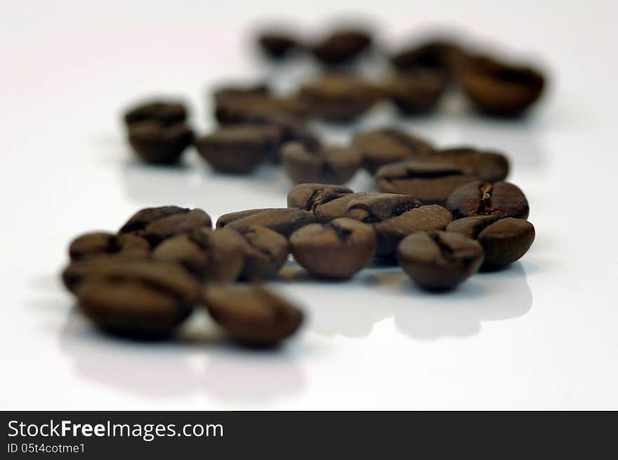 The photograph shows coffee beans placed on a white background. The photograph shows coffee beans placed on a white background.