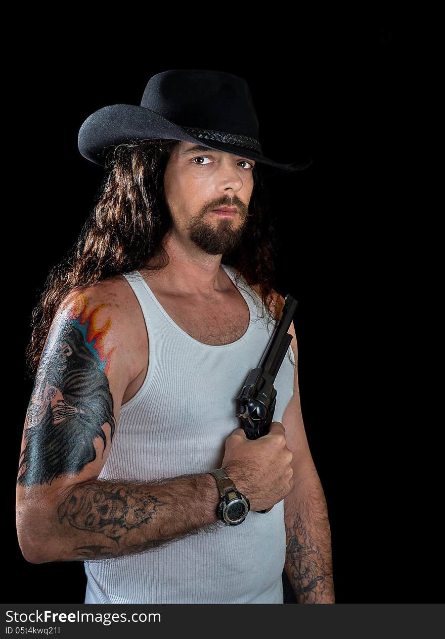 Very handsome man with long wavy brown hair and striking eyes wearing a black cowboy hat holding a revolver. Very handsome man with long wavy brown hair and striking eyes wearing a black cowboy hat holding a revolver