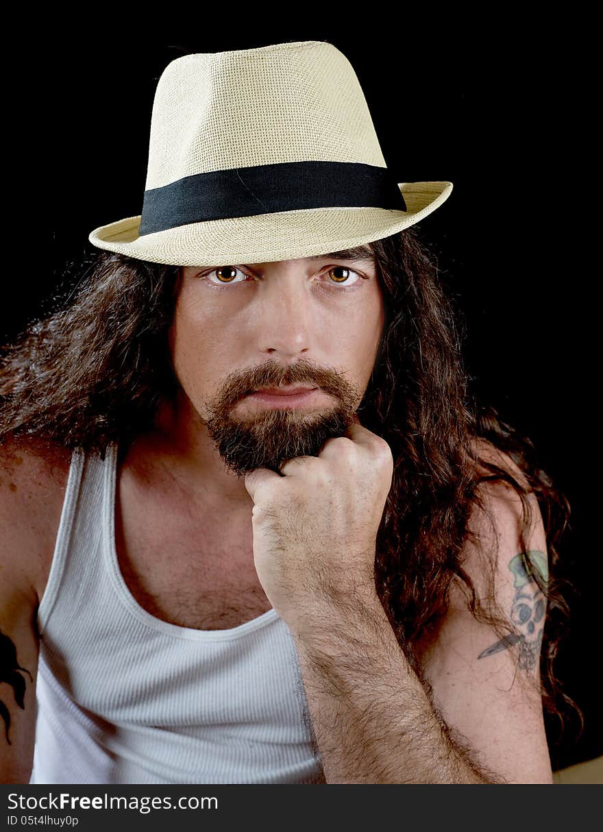 Very handsome man with long wavy brown hair and striking eyes wearing a straw fedora with a black band. Very handsome man with long wavy brown hair and striking eyes wearing a straw fedora with a black band