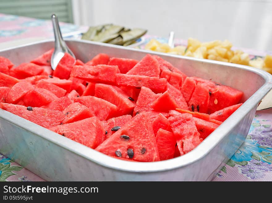 Many watermelons are sliced on tray.