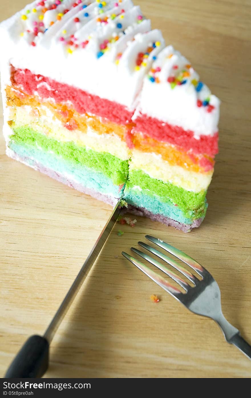 Cutting rainbow cake on wooden table. Cutting rainbow cake on wooden table