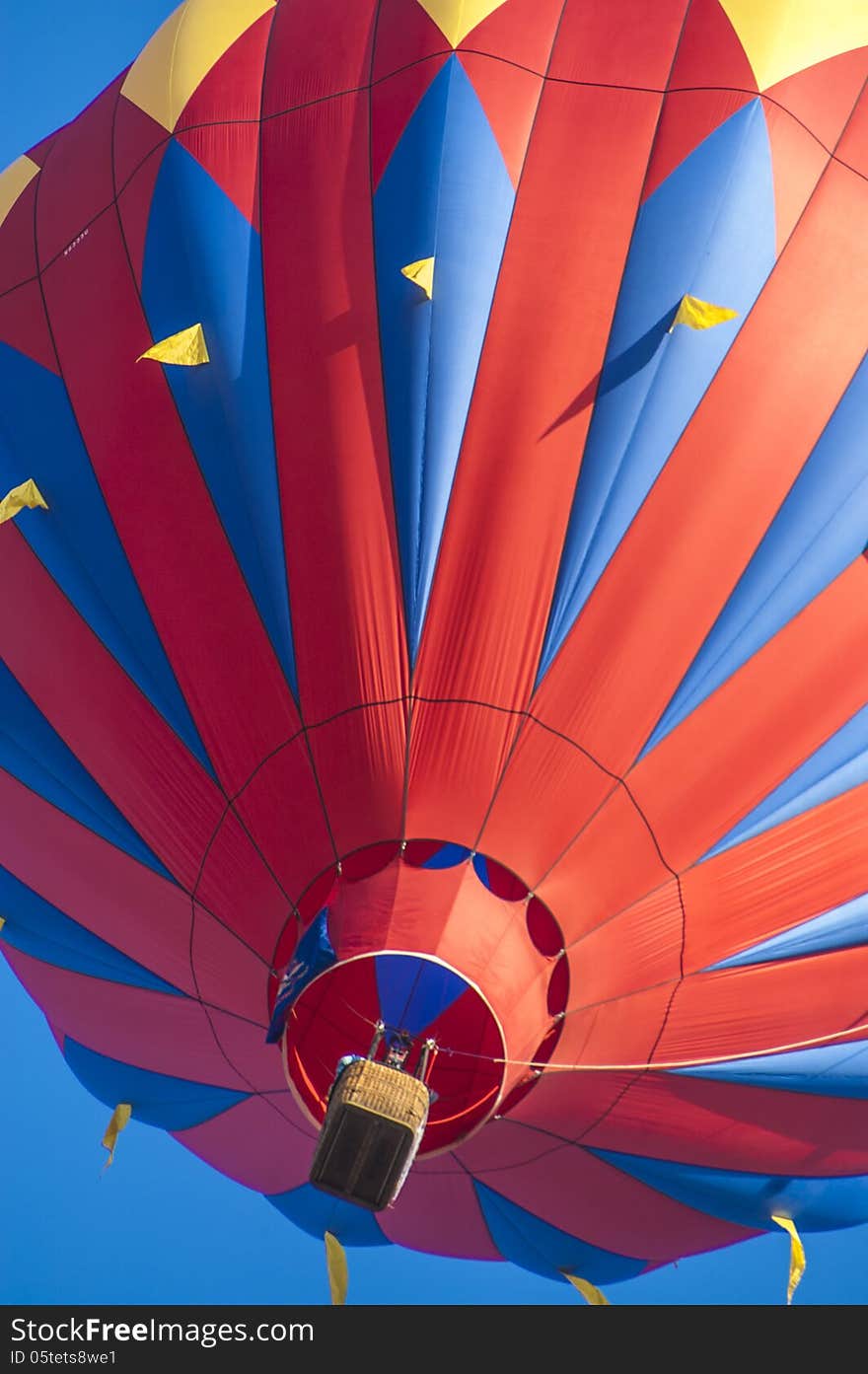 A red hot-air ballon in front of a shiny blue sky.