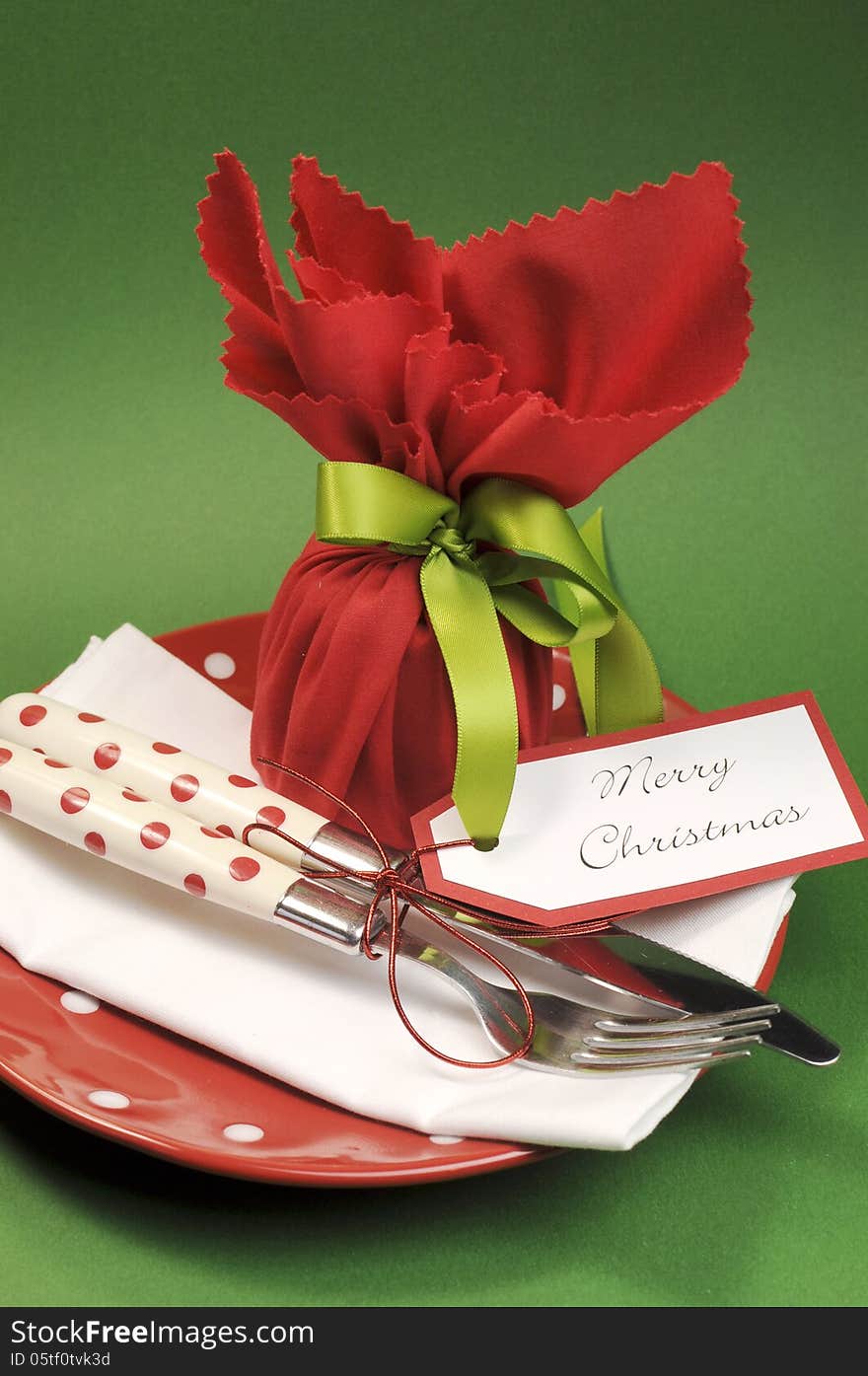 Traditional red and green Merry Christmas dinner or lunch table place setting with individual gift wrapped plum pudding. Vertical. Traditional red and green Merry Christmas dinner or lunch table place setting with individual gift wrapped plum pudding. Vertical.