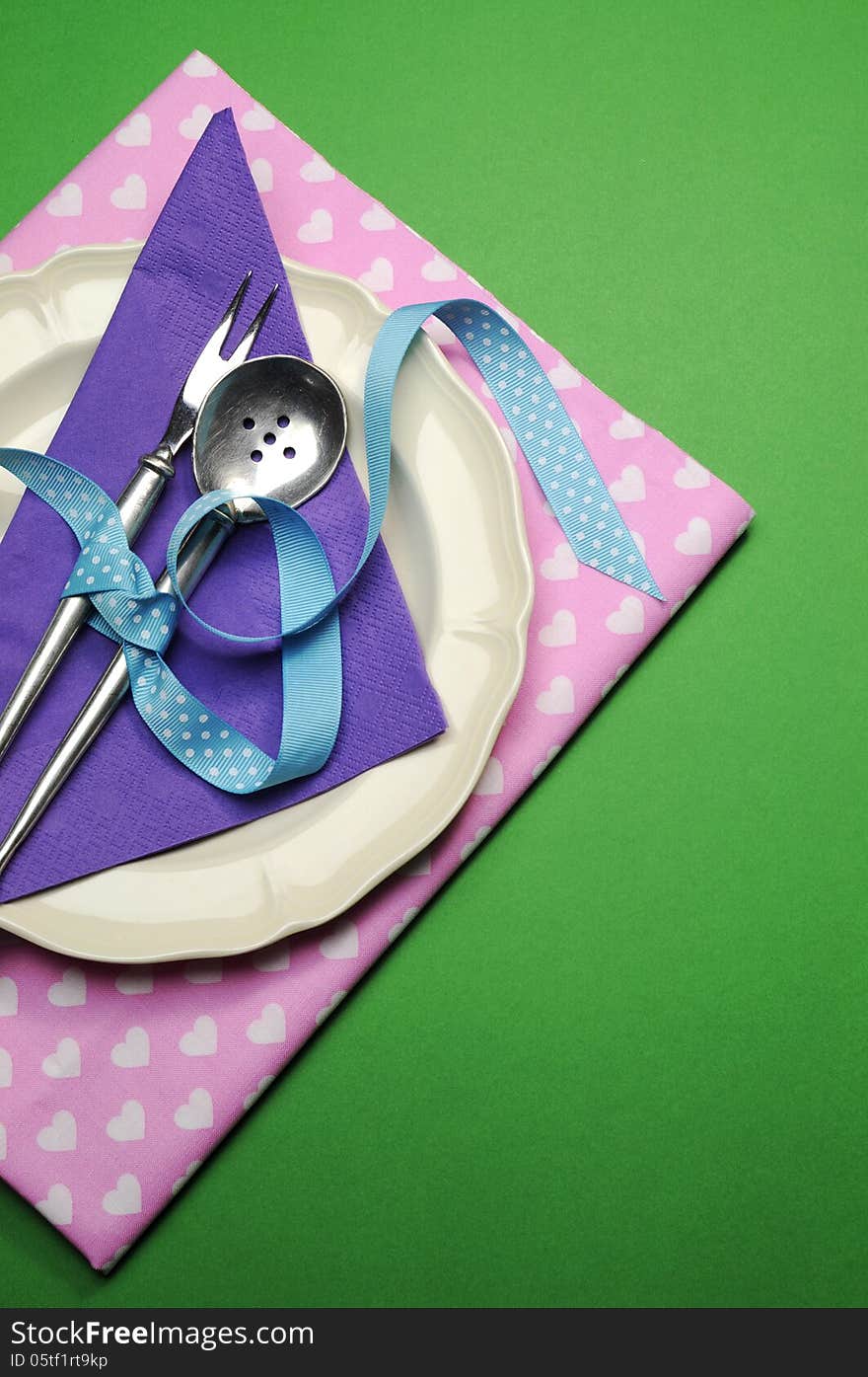 Pretty color dinner or lunch table place setting in green, purple and pink for birthday, modern Christmas, Easter, wedding, Valentine, or Mothers Day. Vertical with copy space for your text here. Pretty color dinner or lunch table place setting in green, purple and pink for birthday, modern Christmas, Easter, wedding, Valentine, or Mothers Day. Vertical with copy space for your text here.