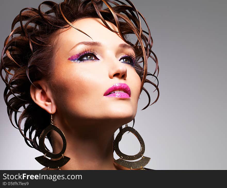 Closeup face of the beautiful woman with fashion creative hairstyle and glamour makeup poses at studio. Closeup face of the beautiful woman with fashion creative hairstyle and glamour makeup poses at studio.