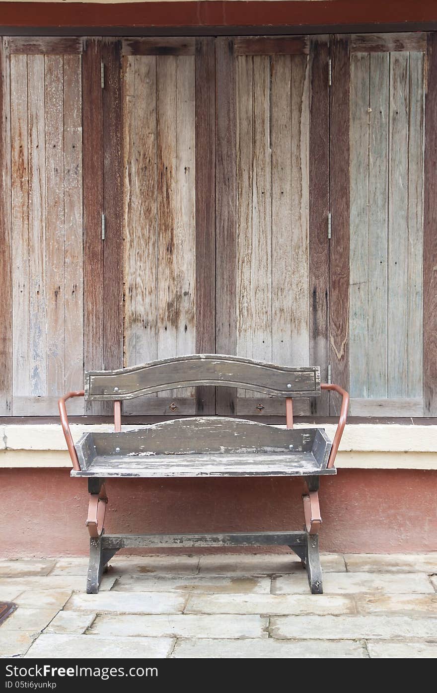 Old wooden bench placed in front of the windows outside the house