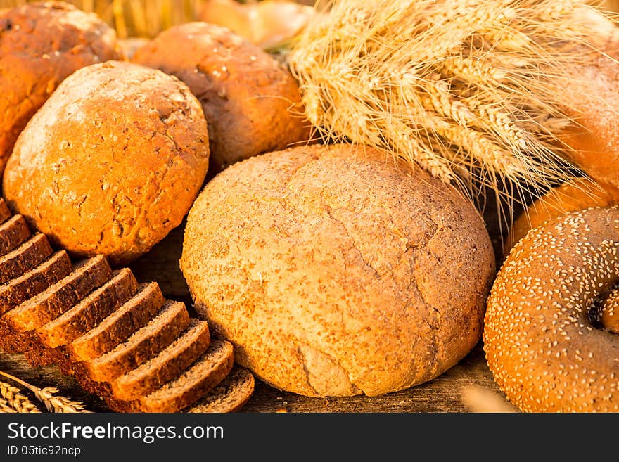 Bread and wheat on the wooden table in autumn field