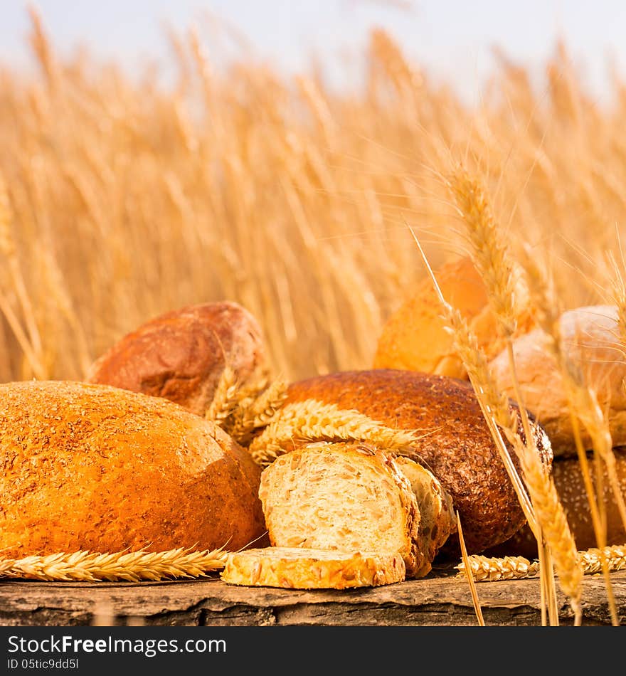 Homemade bread and wheat on the wooden table in autumn field